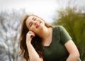 A carefree woman enjoying a sunny day outdoors, expressing pure happiness and relaxation.