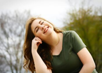 A carefree woman enjoying a sunny day outdoors, expressing pure happiness and relaxation.